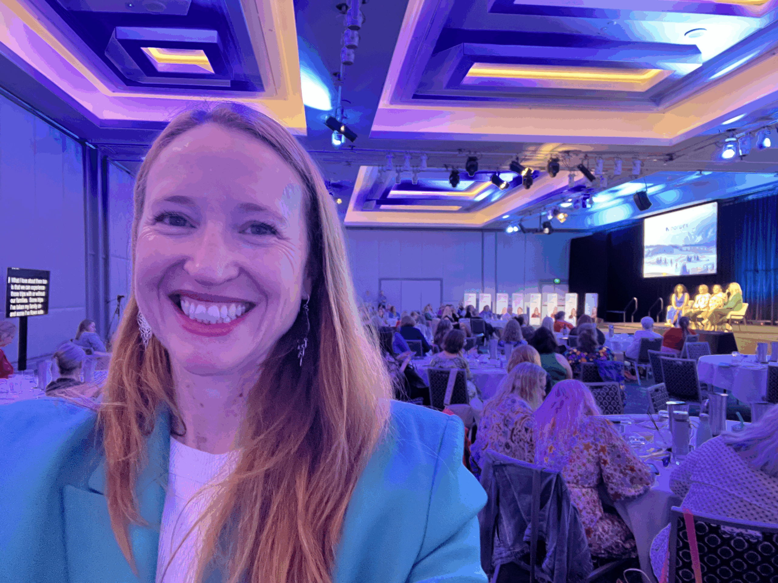 Katrina McCarter, award-winning marketing speaker, on stage presenting to a corporate audience.