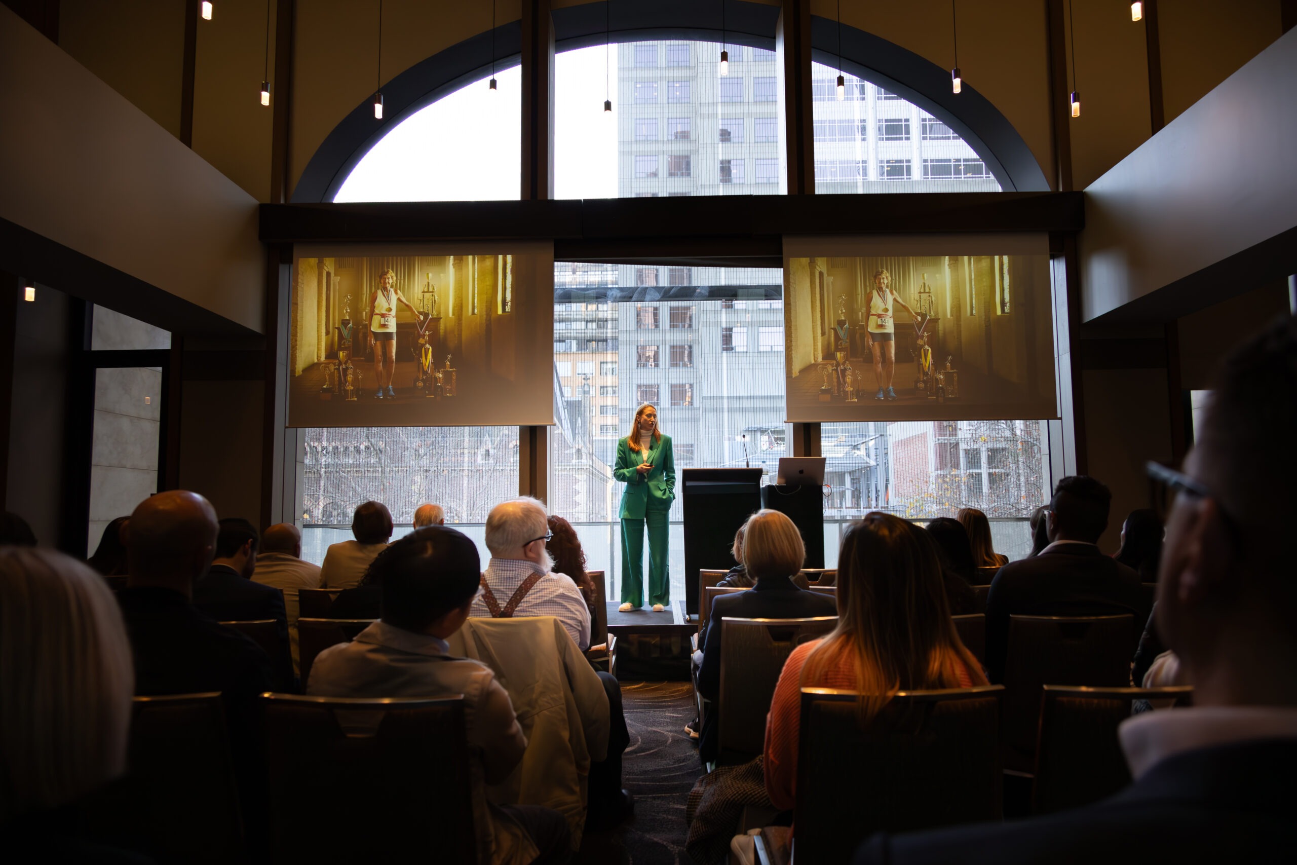 Katrina McCarter, award-winning marketing speaker, on stage presenting to a corporate audience.